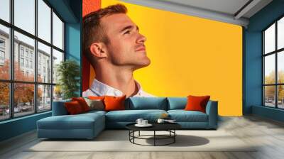  A man stands with eyes closed, head turned to the side before a yellow-red wall Wall mural