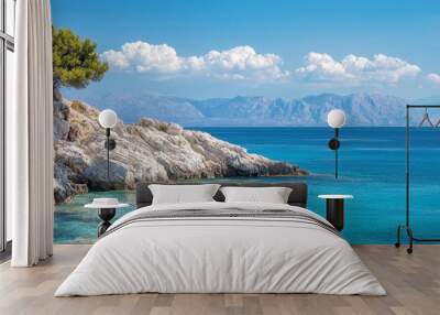  A solitary tree grows on the cliff's edge, overlooking the ocean Mountains distant, blue water near Wall mural