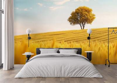  A solitary tree stands in the heart of a golden wheat field, framed by the sun's radiant rays on the horizon Wall mural