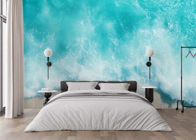  From above, waves crash rhythmically against the sandy shore, while a surfboard glides through the water below Wall mural