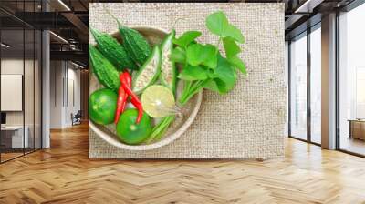 Centella asiatica, bitter melon, Fresh lime and  chili in bamboo basket on sack cloth  Wall mural