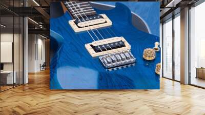 Close up of a vibrant blue electric guitar, with the controls reflected in the high-gloss finish on the body of the guitar. Wall mural