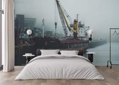 Cargo ship docked in foggy harbor. Wall mural