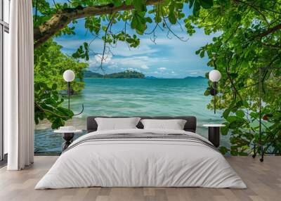 A beautiful beach with a tree in the background. The sky is clear and the sun is shining brightly Wall mural