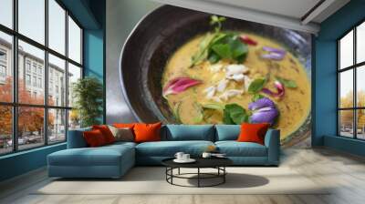 Beautiful and colorful bowl of Thai crab curry garnished with edible flowers at professional Starred restaurant. Modern concept style of Food Styling, creative plating and decorating presentation idea Wall mural