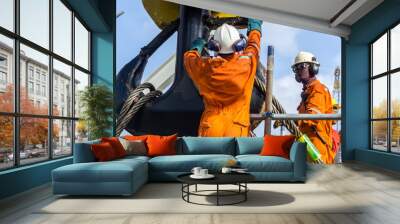 Offshore workers installing a heavy lifting sling onto a crane hook on board a construction work barge at oil field Wall mural