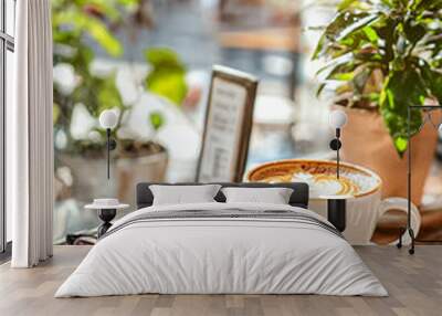 A white coffee cup with a white saucer sits on a table next to a notebook Wall mural