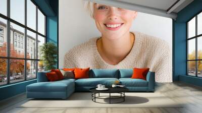 A woman with blonde hair and a white sweater is smiling Wall mural