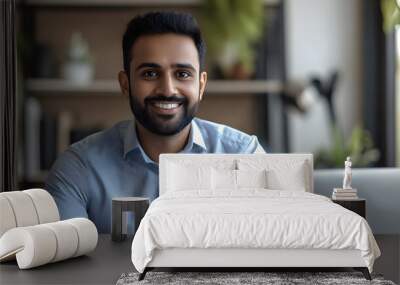 Indian businessman in formal attire smiling while working with a laptop open in front of him. Wall mural