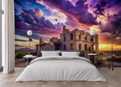 Crumbling casa grande stands tall against a breathtaking backdrop of purple hues, where the sun dips into the horizon, painting the sky with vibrant colors. Wall mural