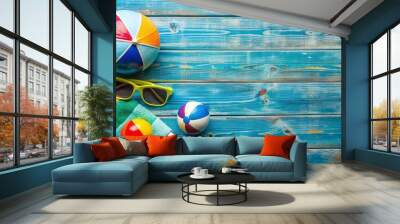 Summer vacation essentials like sunglasses, towels, and beach balls are scattered on a weathered blue wooden board, evoking feelings of relaxation and leisure. Wall mural