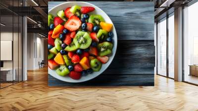 Vibrant bowl of fresh fruit featuring strawberries, blueberries, kiwi, and melons on rustic wood background. Wall mural