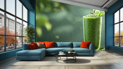 Closeup of a tall glass filled with a vibrant green smoothie garnished with fresh mint leaves against a blurred natural backdrop  The healthy nutritious beverage represents a clean Wall mural