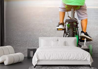 Learning to ride a bike concept, The little boy is practicing cycling a bicycle with the training wheels on the road.  Wall mural