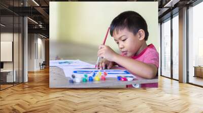 Selective focus. Portrait image of 5 yeas old child boy. Asian student drawing and painting colours on the paper in the room. Study​ from​ home, social​ Distancing, Kid and education concept. Wall mural