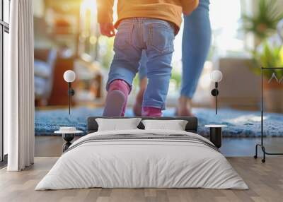 A image of a baby taking their first steps with support from a parent or caregiver, capturing the milestone moment of learning to walk Wall mural