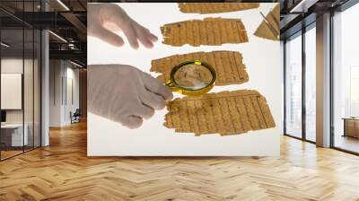 A researcher studies Arabic writing from the Koran using a magnifying glass and a table with a light. Paleography, the study of ancient Arabic writing Wall mural