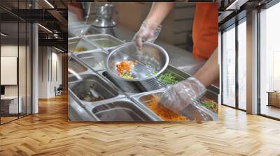 the cook puts pieces of vegetables for salad in a bowl. tray with assorted for salad in the window of a fast food restaurant Wall mural