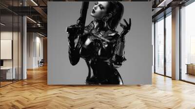 Portrait of a young woman in latex overalls holding a futuristic weapon in her hands Wall mural