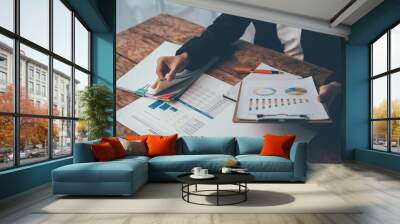 Analyzing the Data: A businessperson meticulously reviews financial data, their hand hovering over a chart filled with key insights. The image captures the essence of strategic planning, financial ana Wall mural