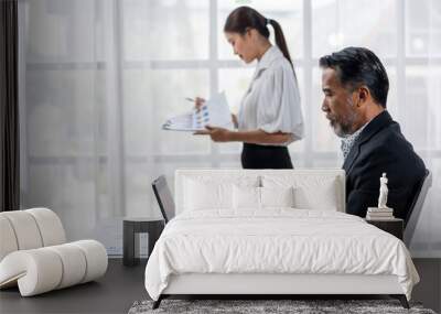 A man and a woman are sitting at a desk with a laptop and papers Wall mural