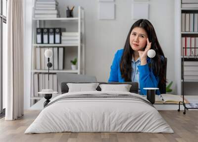 A woman in a blue jacket is sitting at a desk with a laptop and a notebook Wall mural