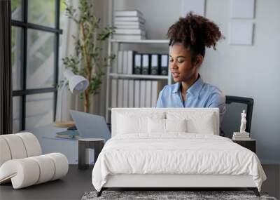 A woman is sitting at a desk with a laptop and a notebook Wall mural