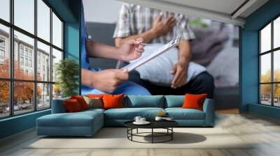 Female doctor taking notes while listening to senior patient describing symptoms Wall mural