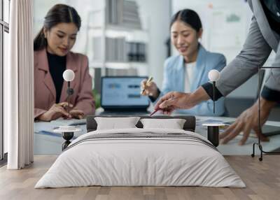 Three women are sitting at a table with a laptop and a few papers Wall mural