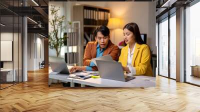 Two people are sitting at a desk with laptops open Wall mural