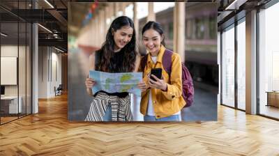 Two women are looking at a map and one of them is holding a cell phone Wall mural