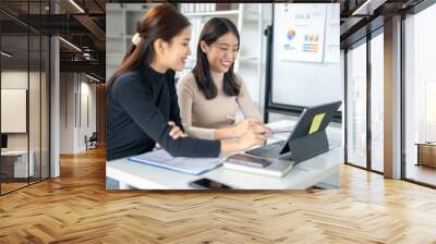 Two women are sitting at a desk with a laptop and a notebook Wall mural