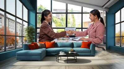 Two women shaking hands in a business meeting Wall mural