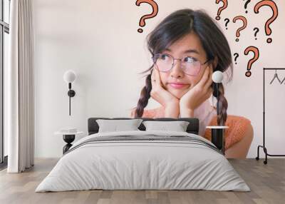 Young asian Student woman thinking with question marks doodles at the back ground with copy space Wall mural