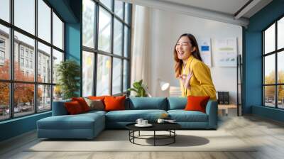 Young manager woman holding laptop is making ok sign and smiling in office Wall mural