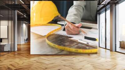 Close-up of female engineer inspecting the blueprint of the building on the desk in workplace, Engineering tools and construction concept Wall mural