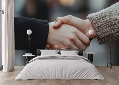 Two hands shake in a gesture of agreement, symbolizing partnership and cooperation.  A close-up of a handshake against a blurry city backdrop. Wall mural