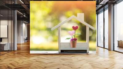 Flower of heart put in the wooden house model on sunlight in the public park, The buying a new real estate as a gift to family or the one loved concept. Wall mural