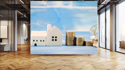 Home model and bottle bank with growing put on the vintage blue background, Saving money for buy house or loan to business investment for real estate concept. Wall mural