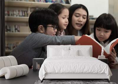 The beautiful lady reading book with three children with happy feeling,blurry light around Wall mural