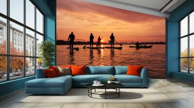 Silhouettes of people standing on SUP (stand up paddle boards) during a beautiful winter sunrise on the river Wall mural