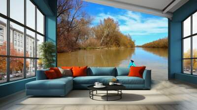 View from the bow of blue kayak on flooded trees during the spring high water on the Danube river. Kayaking in a wild forest among flooded trees. Wall mural