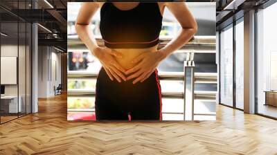 Female athletes, abdominal pain, menstrual period during exercise on walking street in the city. Wall mural