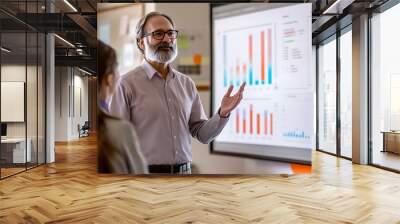 Economy lesson. Experienced professor delivering lecture to classroom of attentive students, using data charts and graphs projected on screen to illustrate key points Wall mural