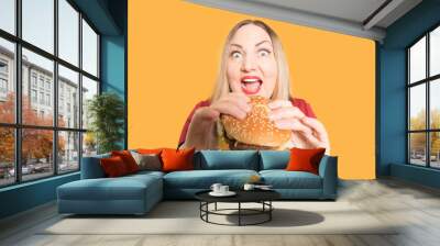 Body positive A hungry woman is biting a big tasty burger . Unhealthy food. Wall mural