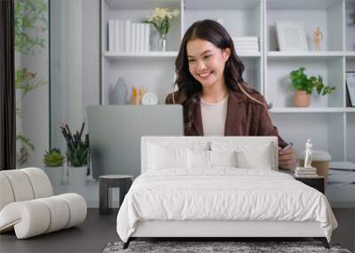 Smiling young female administrative assistant making notes of working planning organizing information in her office. Wall mural