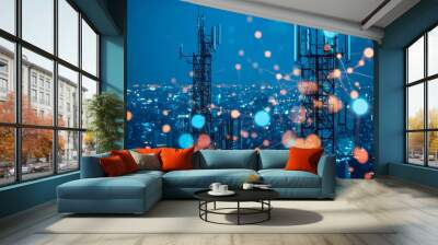 Two cell towers stand tall against a backdrop of a city at night. Wall mural