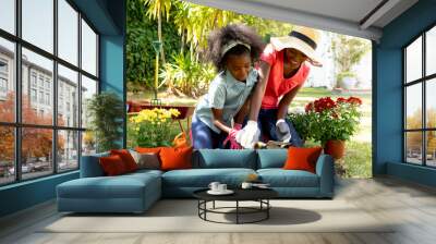 African American girl and her mother planting flowers. Wall mural