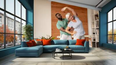 African american male physiotherapist helping caucasian senior woman to perform stretching exercise Wall mural