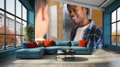 African American man talking to biracial man, both looking happy in a modern business office Wall mural